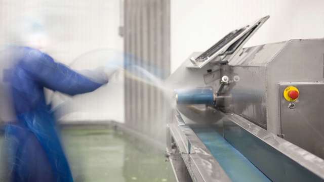 Employee uses cleaning hose at process plant